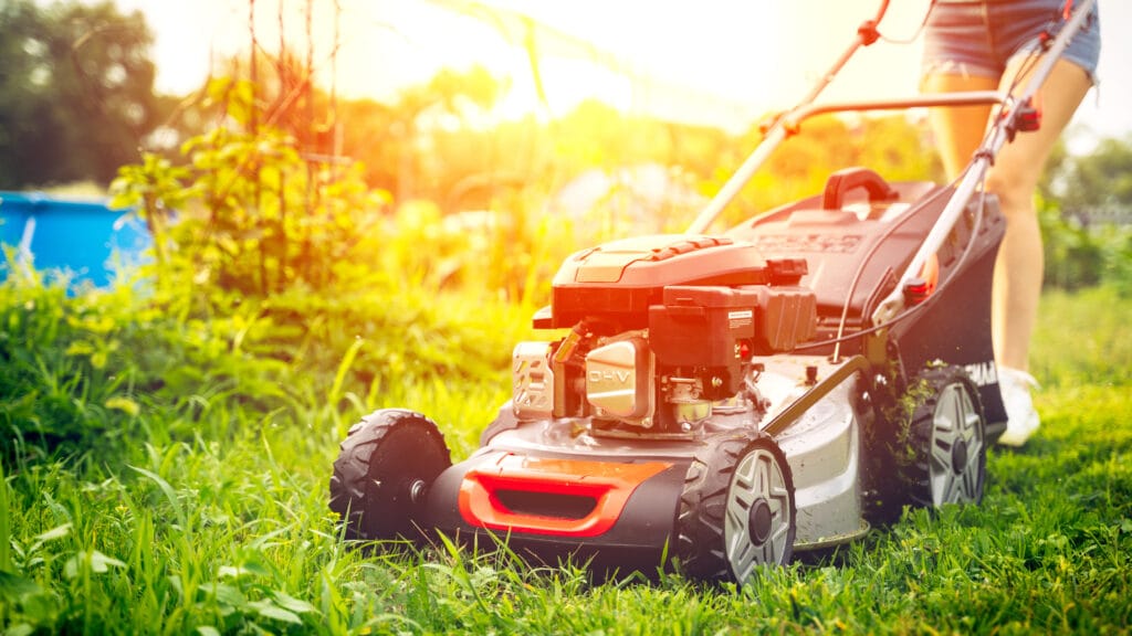 nuori työntää ruohonleikkuria