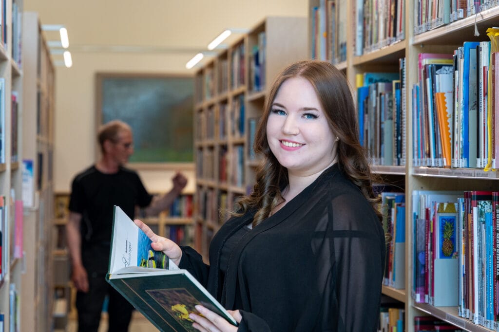 nainen lukee kirjaa kirjastossa