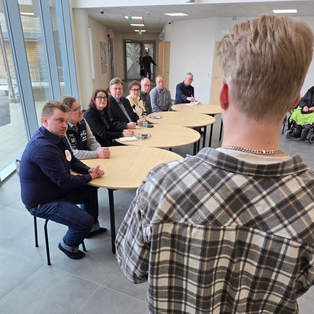 Aluevaalipaneeli Ranuan yläkoulu-lukio Kaarnassa, ehdokkaat istuvat ja selin on toinen juontaja.