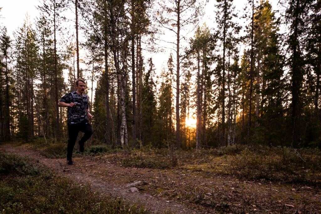 Mies juoksee kuntopolulla metsässä.
