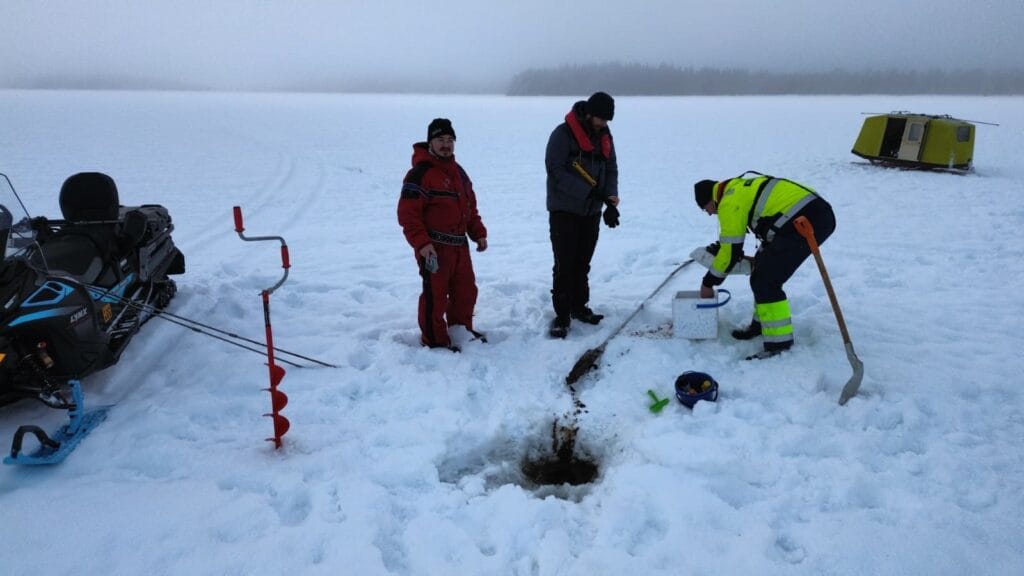 miehet tutkivat talvisen järven pohjaa näytteenotolla.