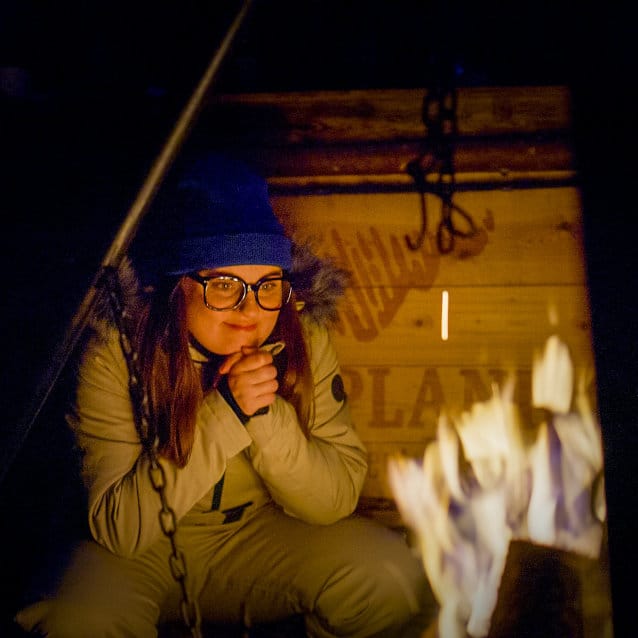 Nainen nuotiolla talvivaatteet yllään.