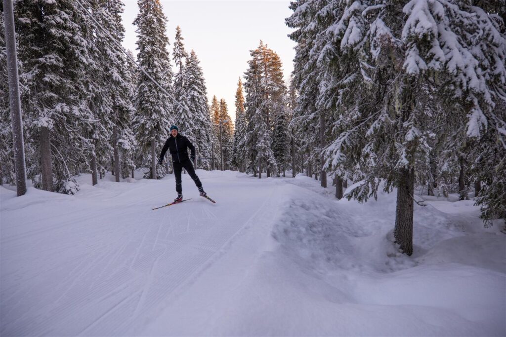 Mies hiihtää luisteluhiihtoa lumisessa metsässä olevalla ladulla.